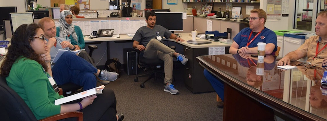 A group of healthcare professionals sitting together in an office, engaged in discussion during a meeting.