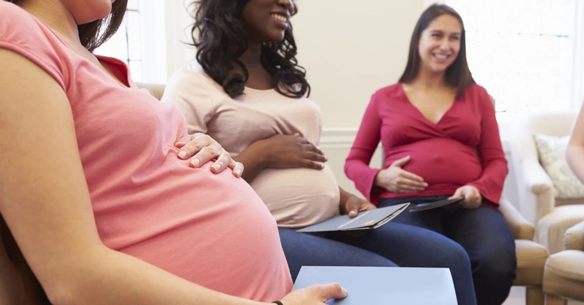 Group of pregnant women sitting together and smiling during a prenatal class or support group.
