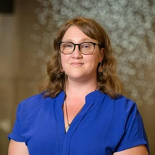 chris_stallman professional photo, wearing a blue blouse, and eye glasses